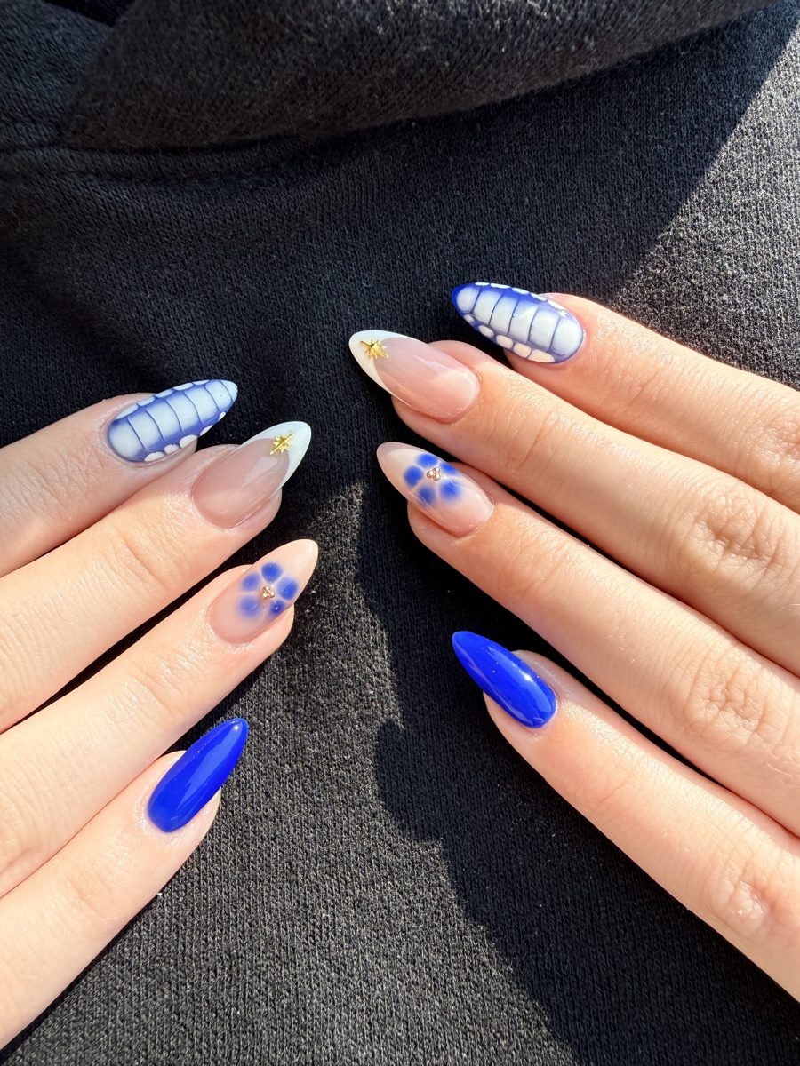 Almond nails alternating cobalt blue, light blue stripes and blue daisies