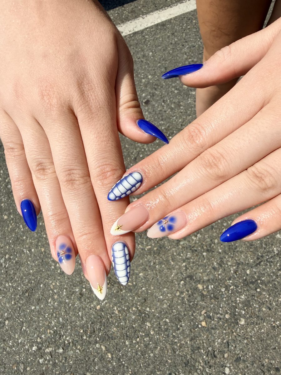 Almond nails in cobalt blue with white daisy and stripe accents