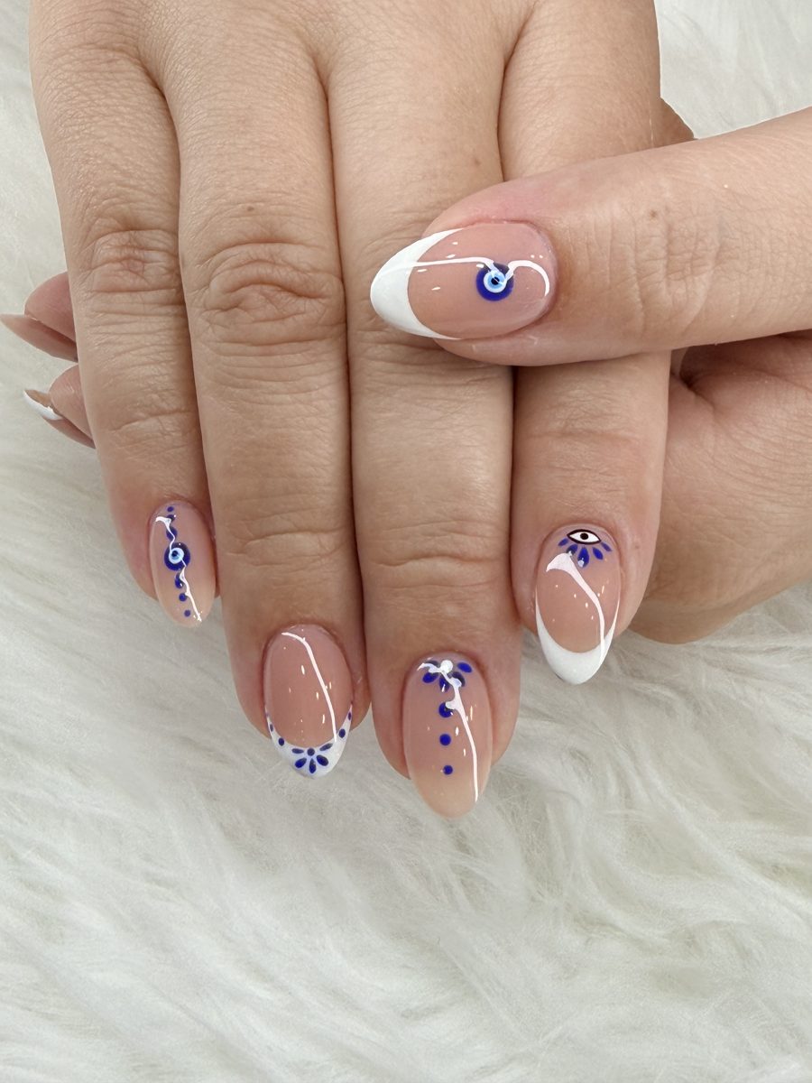 Short almond nails with white French tips and blue evil-eye charms