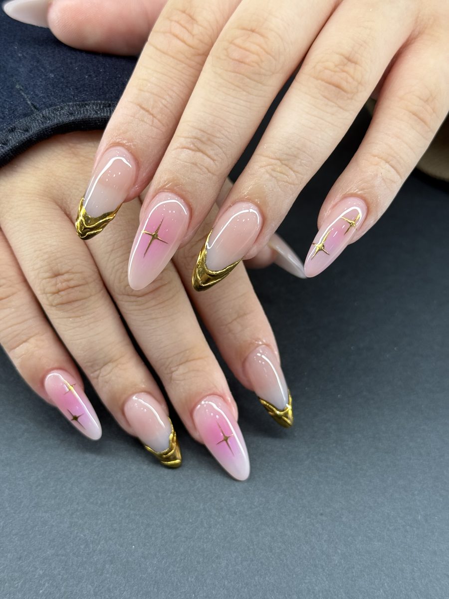 Sheer pink almond nails with gold chrome French tips and gold cross accents