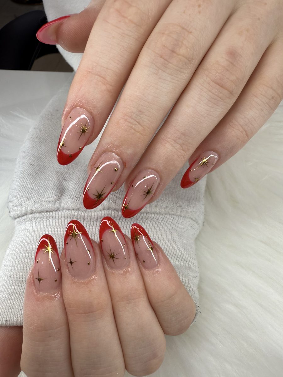 Sheer almond nails with red French tips and gold star accents